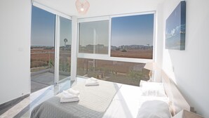 Un dormitorio con un ventanal grande, una cama y vistas al campo.