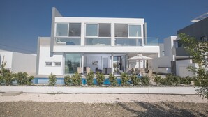 Una casa moderna de dos pisos con balcón, piscina y un jardín cuidado.