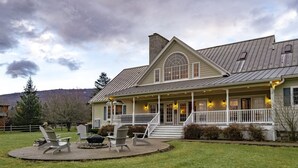 A two-story house with a wrap-around porch, a chimney, and a fire pit with chairs. - Perfect View (Davis)