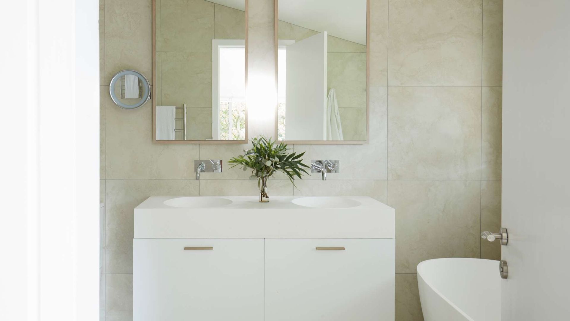 Ein modernes Badezimmer mit zwei Waschbecken, einem großen Spiegel und einer Topfpflanze.