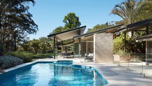 Une maison moderne dotée d’une piscine, d’un espace salon extérieur et d’un jardin.
