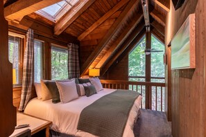 Une chambre confortable avec un grand lit, un bureau et une fenêtre donnant sur un espace verdoyant.