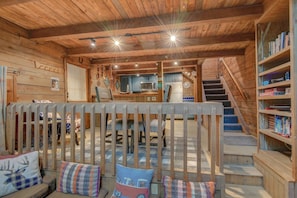 Un interior acogedor de cabaña con escalera de madera, comedor y cocina.