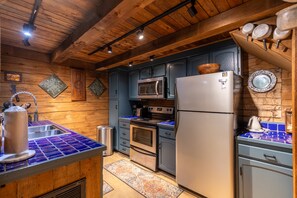Une cuisine avec des murs en bois, un réfrigérateur en acier inoxydable, un four à micro-ondes et une cuisinière.