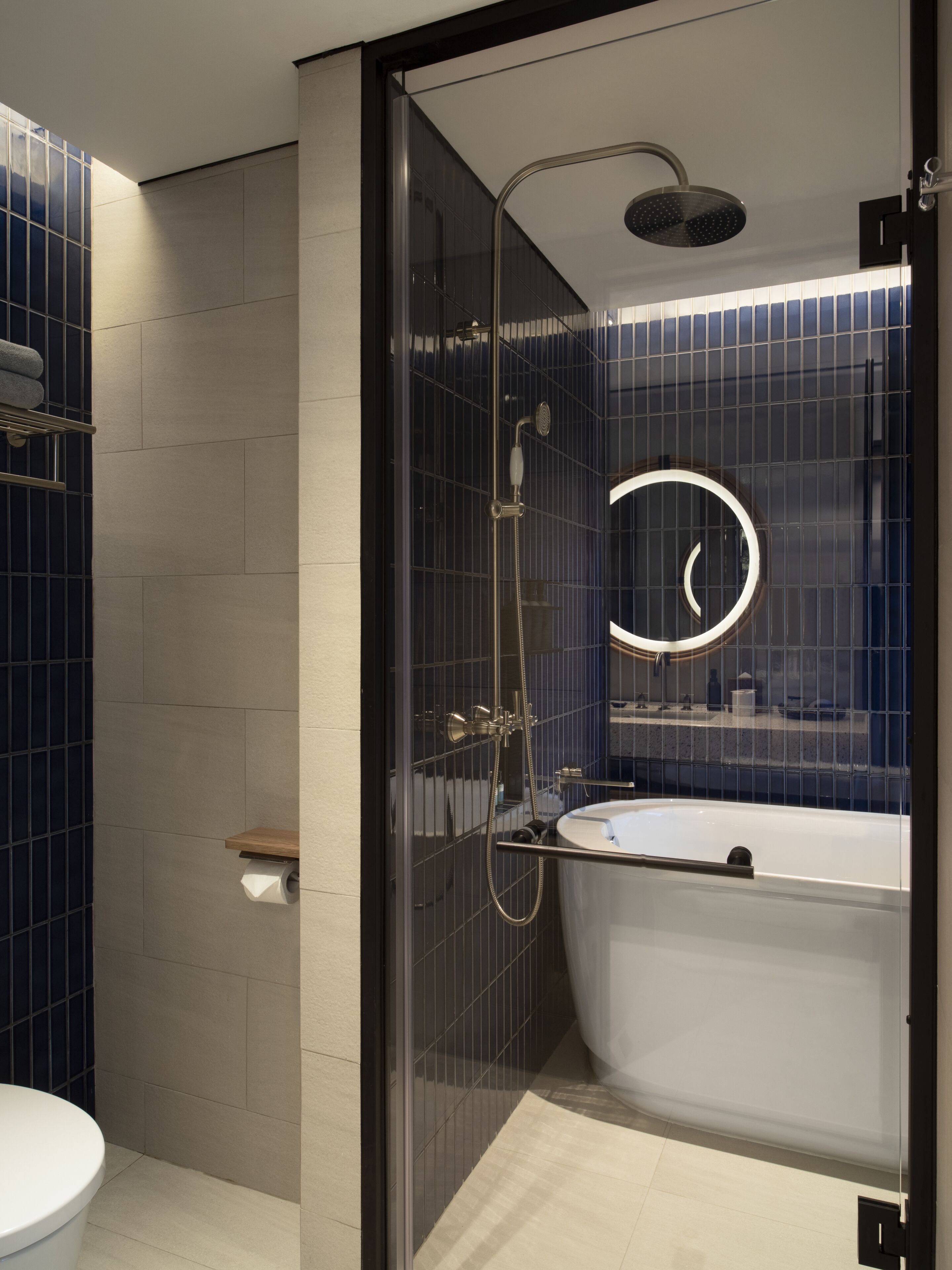 A modern bathroom with a glass-enclosed shower, a freestanding bathtub, and a toilet.