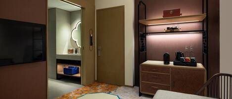 Una habitación de hotel con cama, escritorio, cómoda, espejo y un pequeño rincón de descanso.
