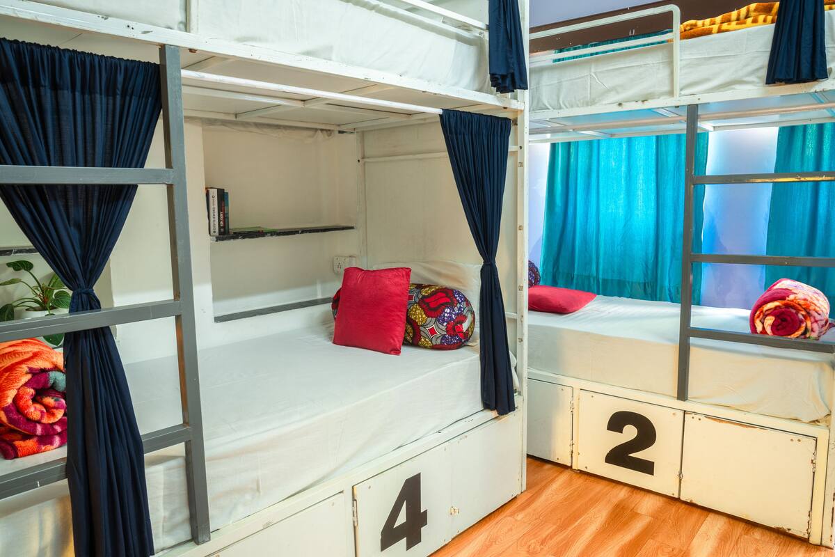 A bunk bed room with curtains, a red pillow, and a number '2' on the side.