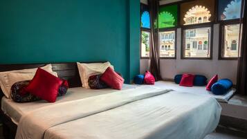 A hotel room with two beds, teal walls, and windows with traditional architectural views.