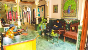 A lobby with a reception desk, seating area, and decorative elements including a peacock painting. - Dreamyard Udaipur - Hostel (Udaipur)