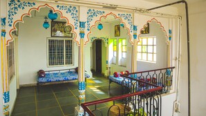 A room with a staircase, a bench, and a table with a patterned tablecloth. - Dreamyard Udaipur - Hostel (Udaipur)