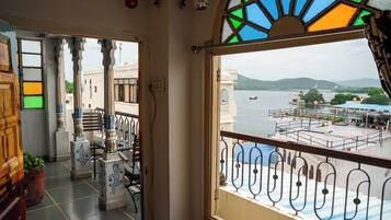 A room with a view of a body of water, a balcony with a railing, and a window with stained glass.