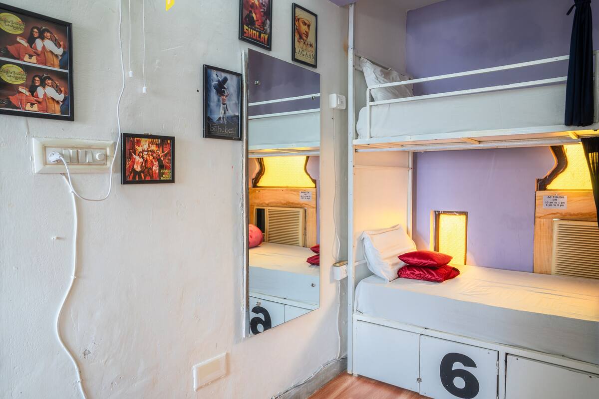 A dormitory room with bunk beds, a mirror, and wall decorations.