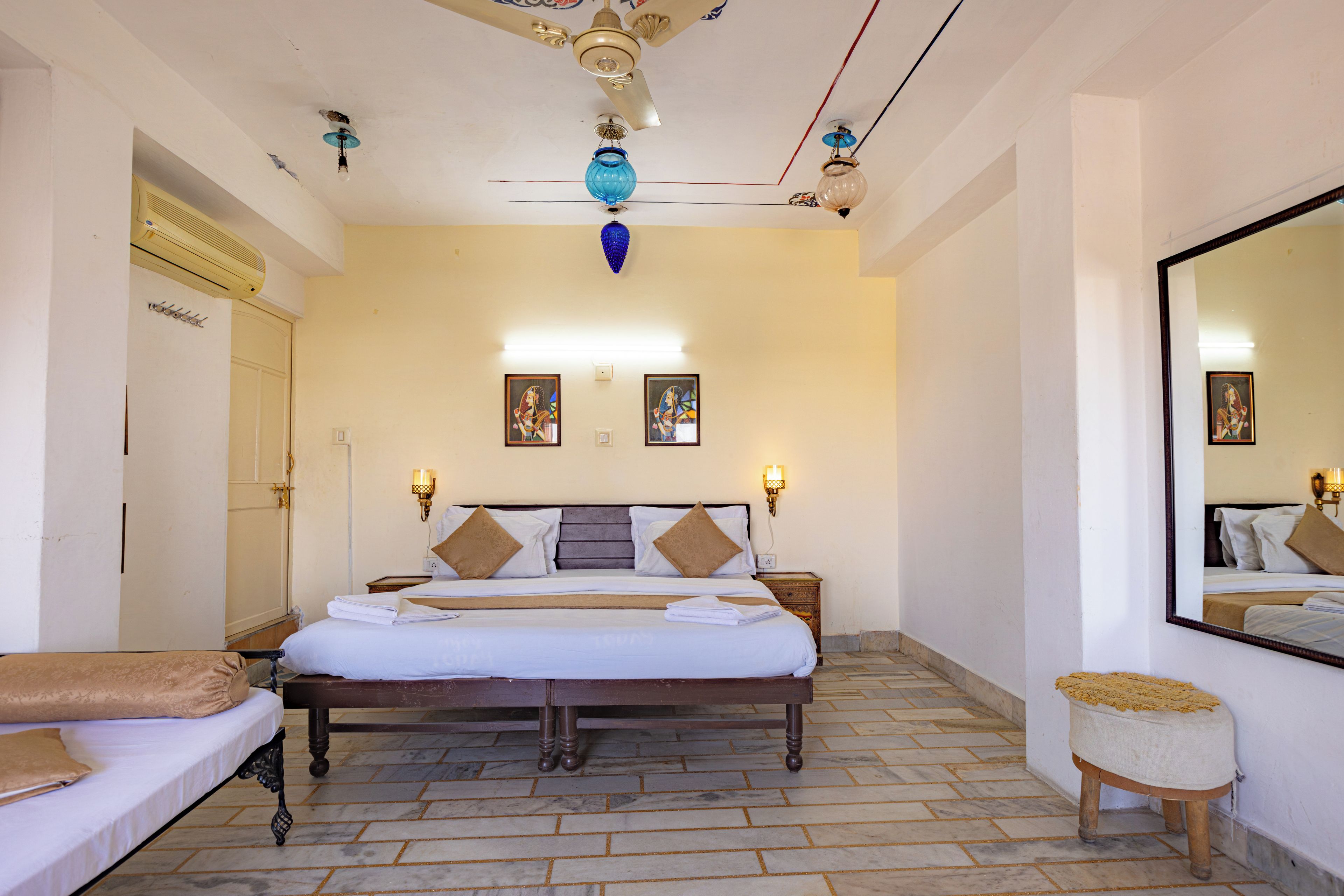 A hotel room with a large bed, a wardrobe, a mirror, and a ceiling fan.