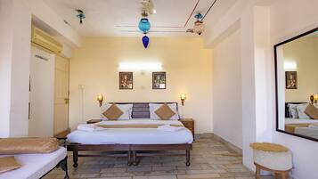 A hotel room with a large bed, a wardrobe, a mirror, and a ceiling fan.