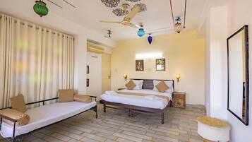 A room with a bed, a sofa, a small table, and a decorative ceiling.