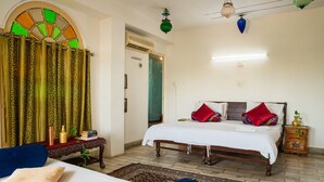 A bedroom with a bed, a nightstand, a table, and a chair. - Dreamyard Udaipur - Hostel (Udaipur)