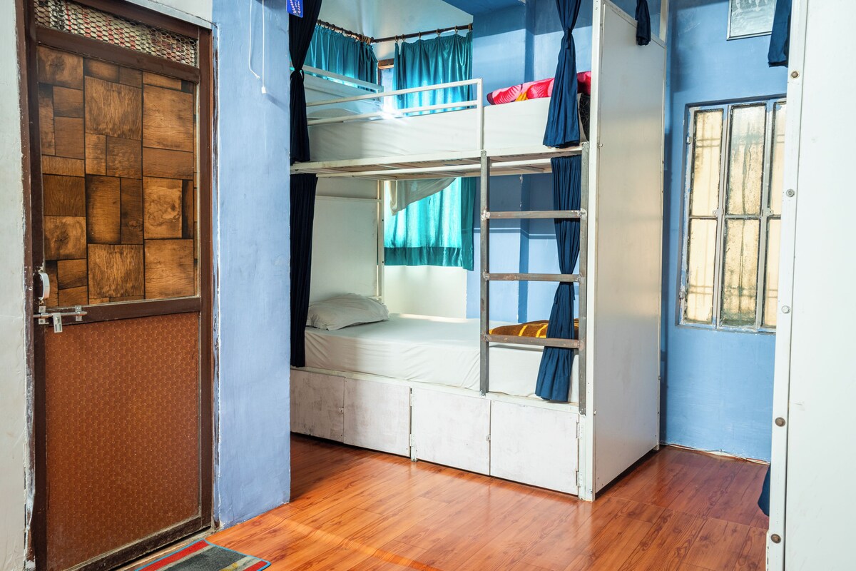 A room with bunk beds, a wooden door, and a window with curtains.