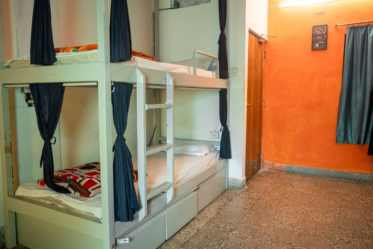 A bunk bed room with curtains, a small table, and a wall with a poster.