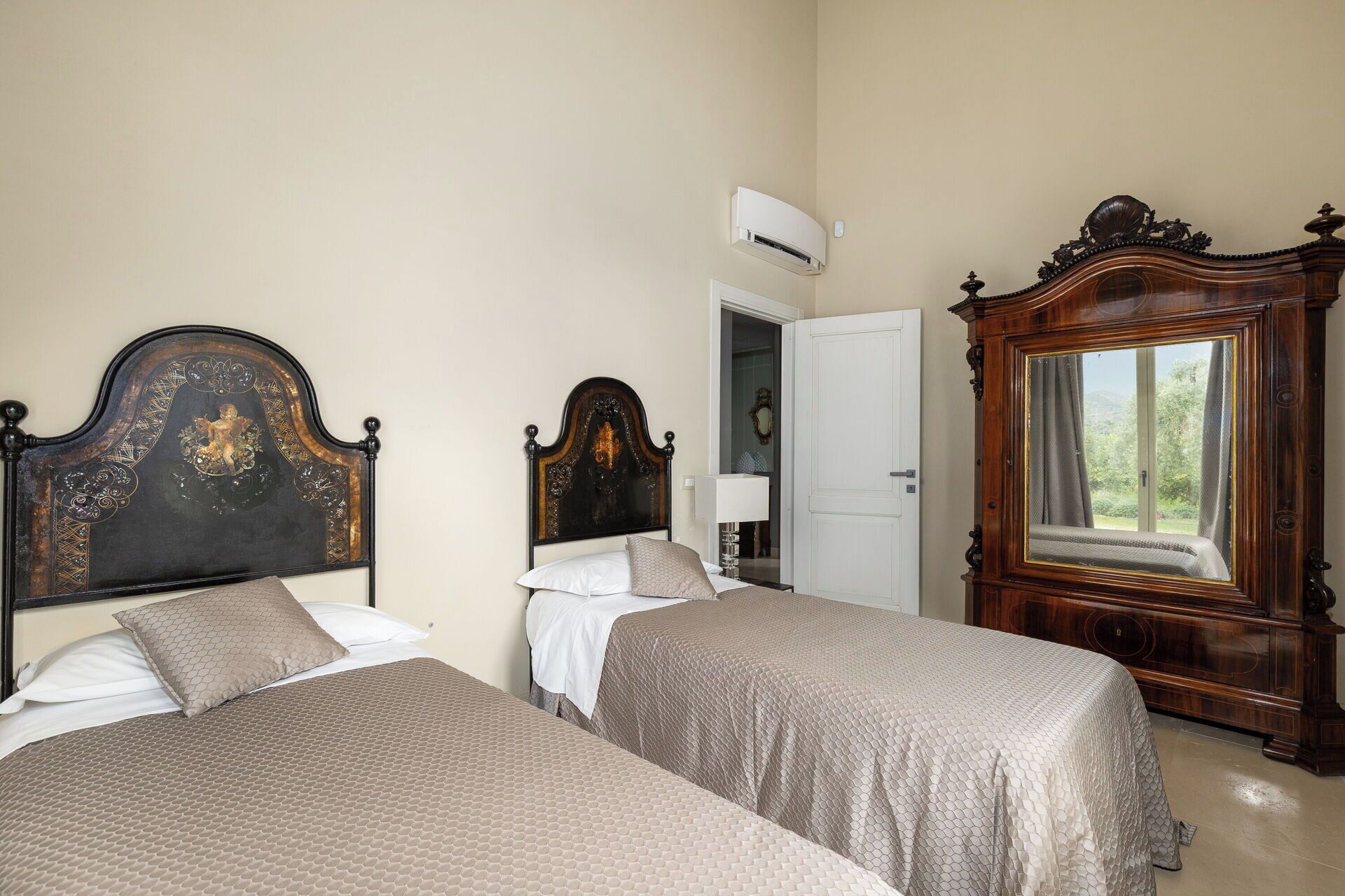 A room with two beds, a wardrobe, and a mirror.