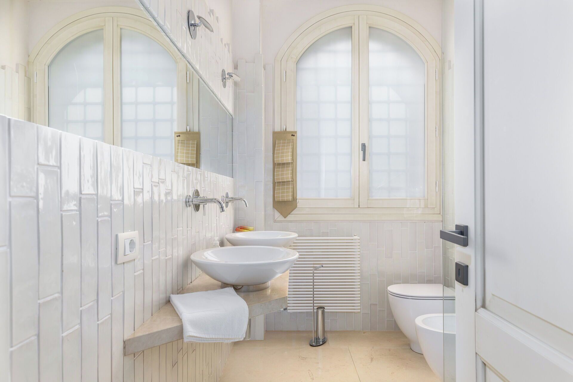 Ein Badezimmer mit zwei Waschbecken, einer Toilette und einem Fenster.