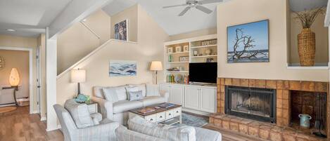 A spacious living room with a fireplace, a television, and a bookshelf.