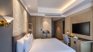 A modern hotel room with a large bed, a desk with a flat-screen TV, a seating area, and a minibar. - Aber Khamis Mushait (Khamis Mushait)