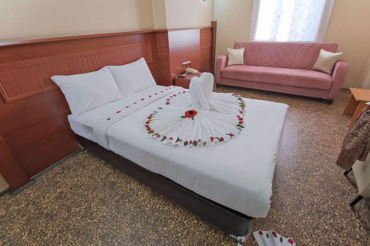 Een hotelkamer met een bed, een roze bank en een klein houten bijzettafeltje.
