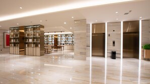 A spacious lobby with a polished marble floor, a central seating area, and a modern elevator.