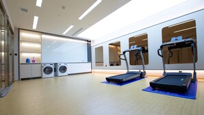 A modern gym with treadmills, a washing machine, and a large mirror.