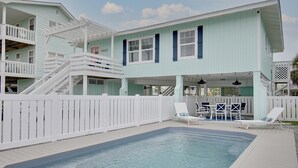 A two-story house with a swimming pool, white railings, and outdoor furniture.