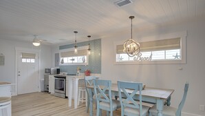 A kitchen with white cabinets, a microwave, and a dining area with blue chairs and a table.