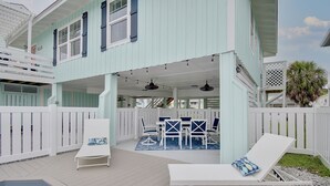 A two-story house with a covered patio, outdoor seating, and a hot tub.