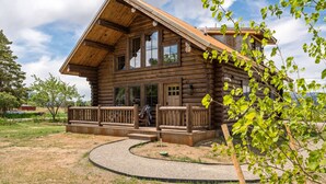 A log cabin with a porch, large windows, and a gravel driveway. - Beautiful Log Cabin in Paradise Valley, Montana (Livingston)