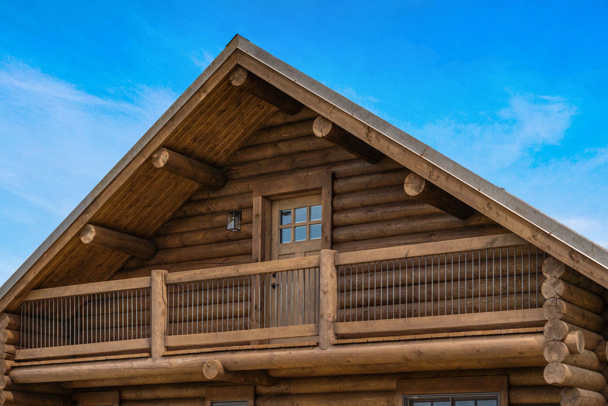 Une cabane en rondins dotée d’un balcon et d’une lucarne.