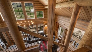 A wooden interior with a spiral staircase, large windows, and a bear picture. - Beautiful Log Cabin in Paradise Valley, Montana (Livingston)