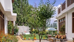 A well-maintained garden with a variety of flowers, a lawn, and a seating area with outdoor furniture. - Hotel Malik Residency (Leh)