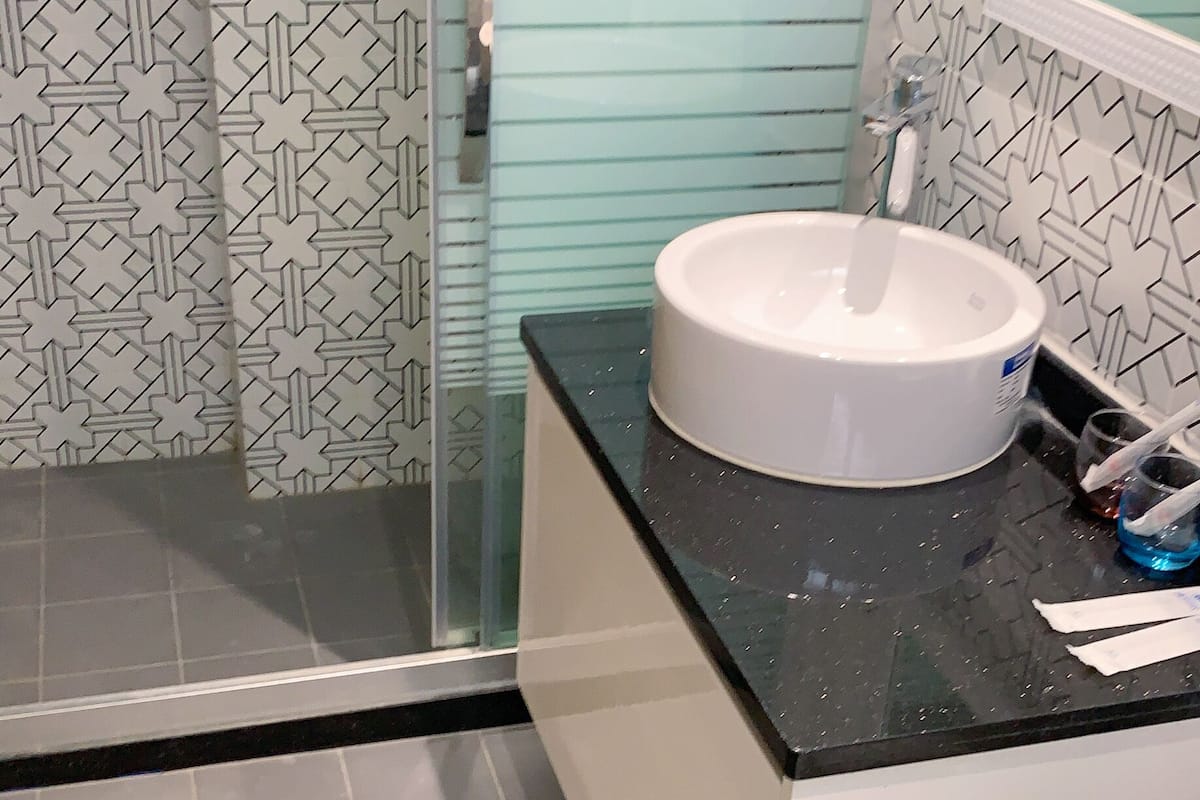 A bathroom with a glass shower enclosure, a white sink, and a toilet.