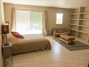 A bedroom with a large bed, a sofa, a small table, and a bookshelf.