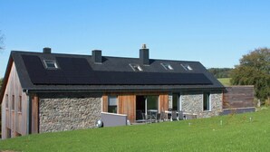 Una casa moderna con techo inclinado, fachada de piedra y un amplio patio descubierto.
