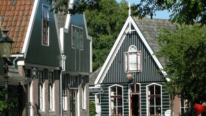 A traditional building with a steeply pitched roof, large windows, and a visible sign indicating a business. - Charming Home by the Lake (West-Grafdijk)