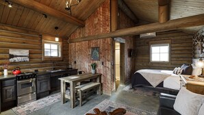 Een blokhut van binnen met een keuken, eethoek en slaapkamer.