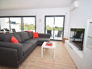 A modern living room with a grey sectional sofa, a white coffee table, and a flat-screen TV. - Comfortable villa in Coto with swimming pool (Coto)
