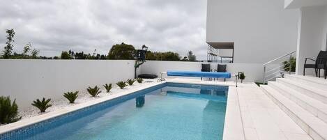 Een verwarmd zwembad, ligstoelen bij het zwembad