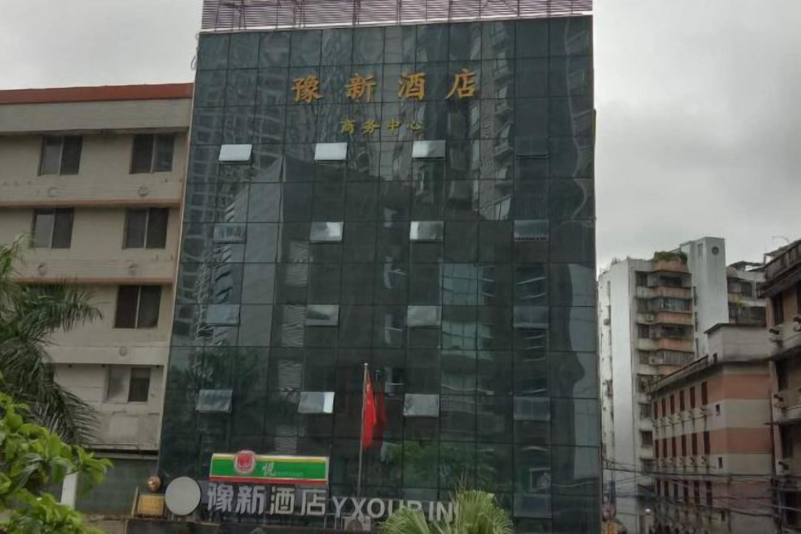 Een modern hotelgebouw met een glazen gevel, een vlag en borden die aangeven dat het een nieuwe zaak is.