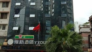A modern building with a reflective glass facade and a red flag on top.