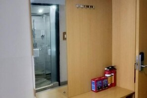 A hotel room with a wooden door, a small table with a fire extinguisher and a box of tissues.