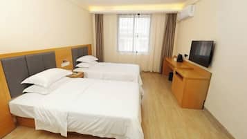 A hotel room with two beds, a desk, a television, and a window with curtains.