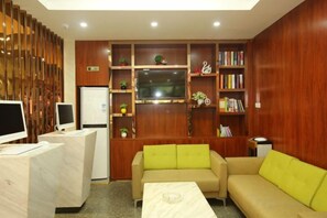 Un vestíbulo de hotel con mostrador de recepción, zona de estar y una gran pantalla de televisión.