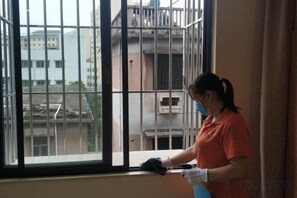 Una persona limpiando un ventanal con un pulverizador.