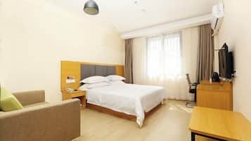 A hotel room with a bed, a desk, a chair, and a television.